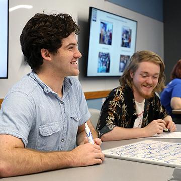 Two male students smile while in class. 